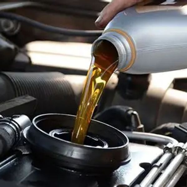 Pouring motor oil into a car engine for maintenance.