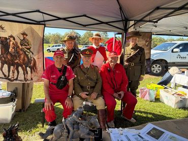 Group of people in historical and modern costumes at an outdoor event booth.