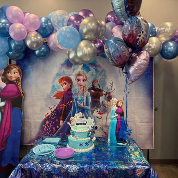 Frozen-themed birthday party setup with balloons and cake.