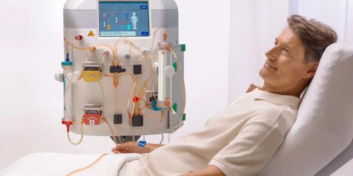 Man receiving dialysis treatment while resting on a medical chair.