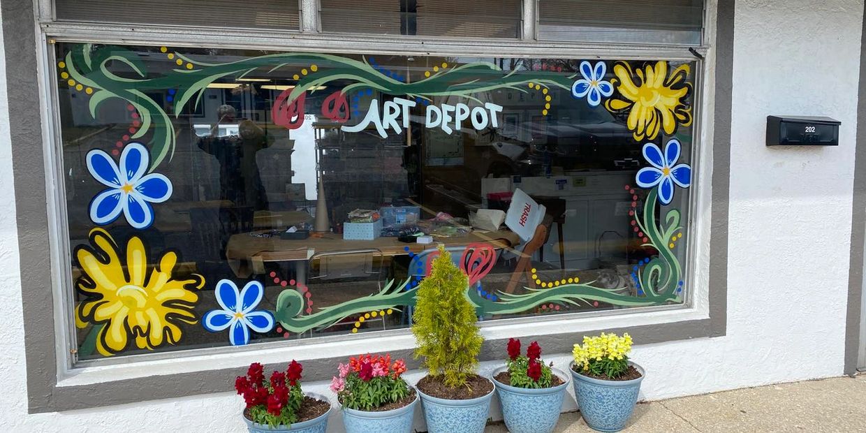 Colorful floral window art with potted plants outside an art store.