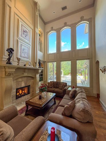 Elegant living room with tall windows, cozy fireplace, and plush seating.