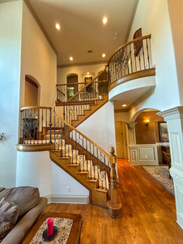 Elegant wooden staircase with wrought iron railing in a spacious home interior.