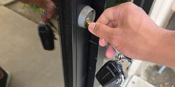 A person unlocking a glass door with keys in hand.