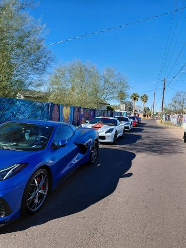 A line of sports cars parked along a street with colorful murals.