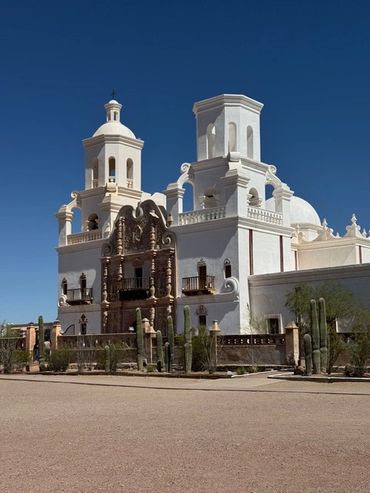 Historic white mission church with ornate façade under clear blue sky.