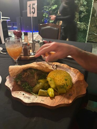 A wooden plate holding a meal with rice, vegetables, and bread.