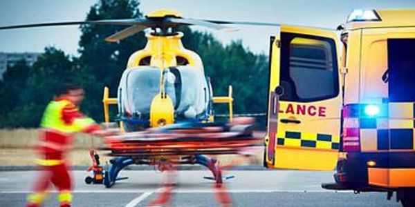 Emergency responders transporting a patient to a helicopter and ambulance.