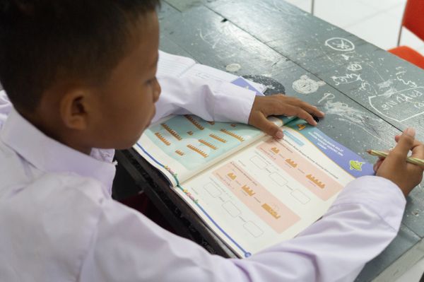 Child studying a workbook at a desk.