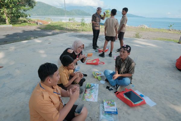 Group of people sitting and standing outdoors near a scenic beachfront.