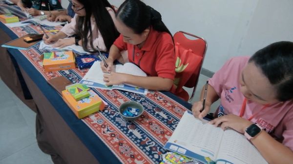 People writing in notebooks at a table.