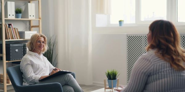 Two women engaged in a counseling session in a cozy, well-lit room.