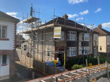 A house surrounded by scaffolding on a sunny day.