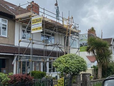 House under construction with scaffolding and cloudy sky.