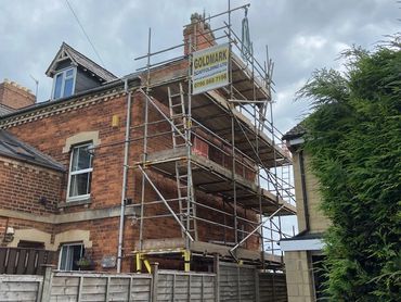 Scaffolding erected around a brick house for construction work.