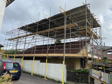 Scaffolding erected around a house with a tiled roof for renovation.