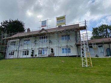 A house with scaffolding on the exterior under a cloudy sky.
