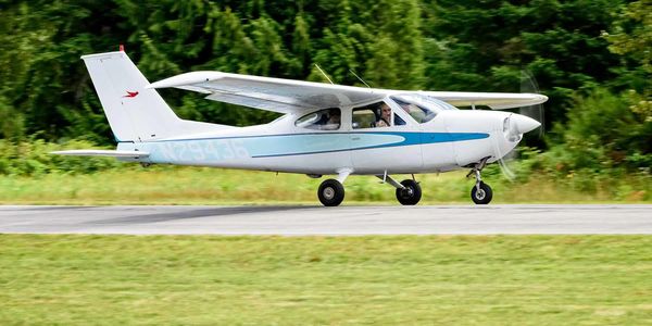 Small white and blue single-engine airplane taxiing on runway.