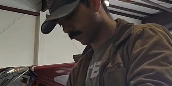 Man wearing a cap and jacket, concentrating indoors.