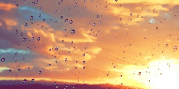 Raindrops on glass with a sunset sky in the background.
