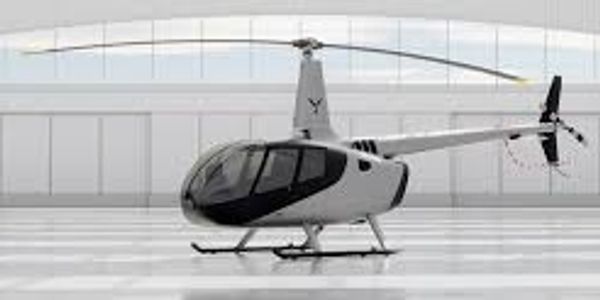 A sleek white helicopter inside a spacious hangar.