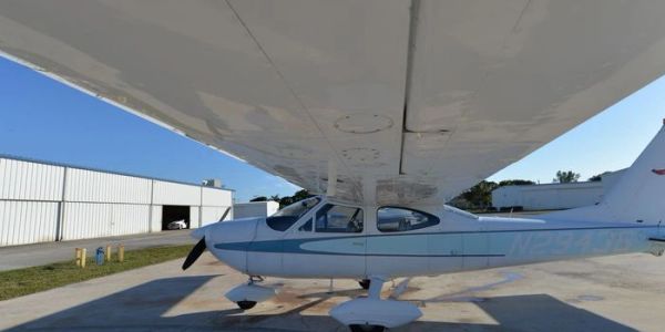 Small single-engine airplane parked on a concrete surface.