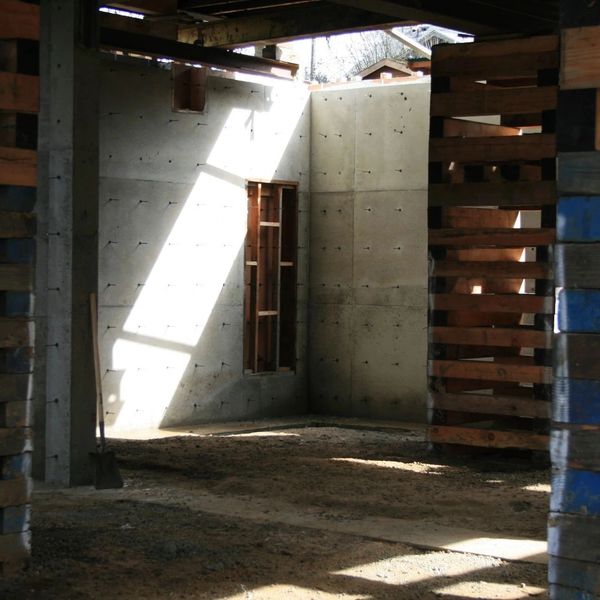 Sunlight illuminates a concrete room under construction with wooden supports.