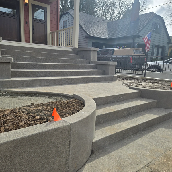 Concrete steps and curved planters in front of a house during construction.