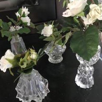 White roses in clear glass vases on a dark surface.