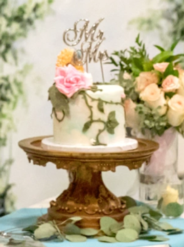 Elegant wedding cake with floral decorations and "Mr &amp; Mrs" topper.