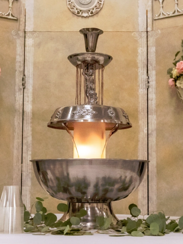 Silver chocolate fountain on a decorated table.
