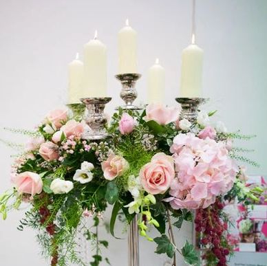 Elegant floral centerpiece with candles and pink roses.