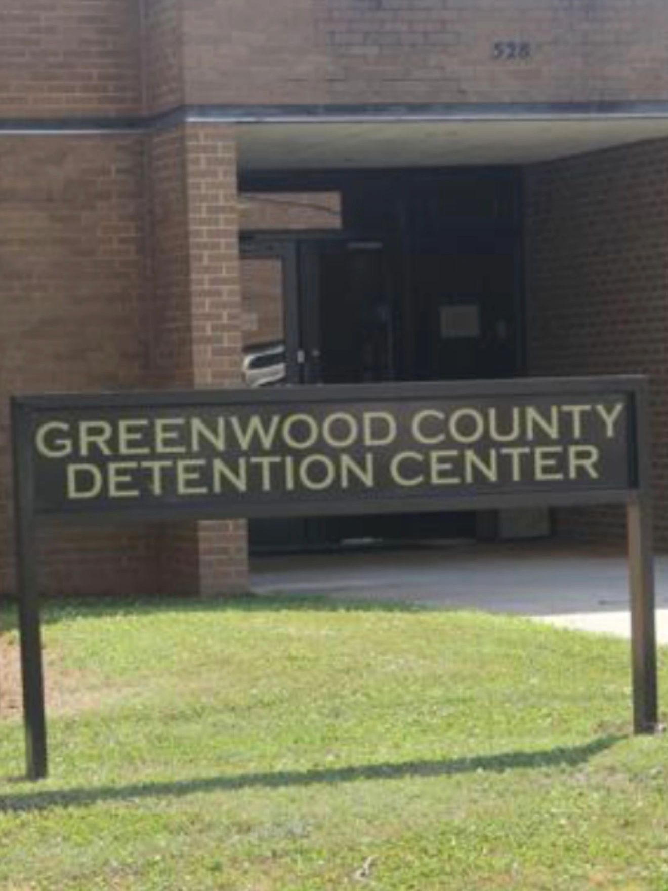 Sign for Greenwood County Detention Center outside a brick building.