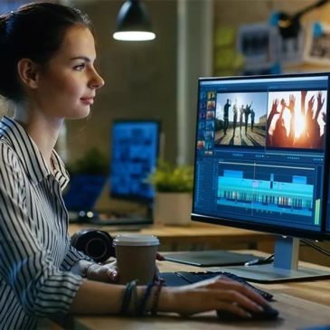 Woman editing video on a desktop computer in a cozy workspace.