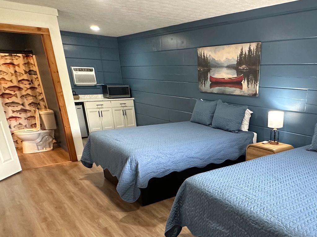 Cozy room with blue walls, two beds, and a fish-themed bathroom.