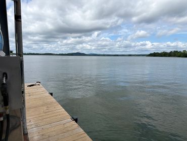 Calm lake view with a wooden dock and cloudy sky.