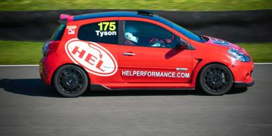 Red race car with number 175 and HEL logo speeding on a track.
