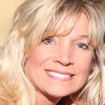 Smiling blonde woman with light eyes.