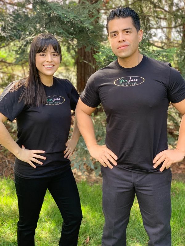 A Brother and Sister in the woods smiling at the camera wearing company shirts
