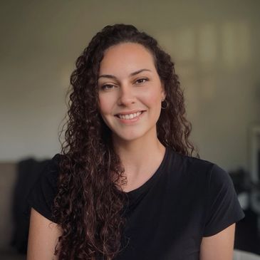 A smiling woman with curly hair wearing a black shirt.