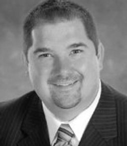 Black and white portrait of a smiling man in a suit and tie.