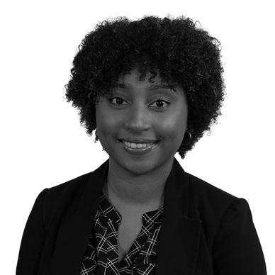 Professional portrait of a smiling woman with curly hair in business attire.