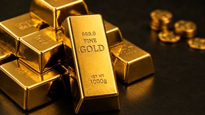 Stack of gold bars with coins in the background.