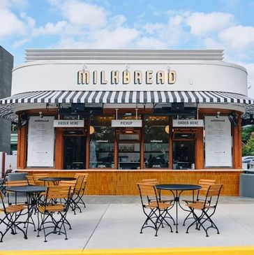 Milk Bread cafe with outdoor seating and striped awning.