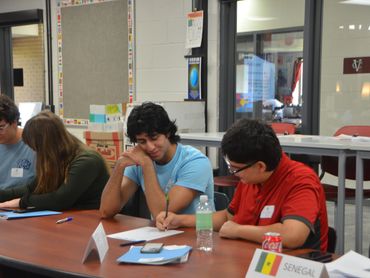 Three students sit at a table writing.