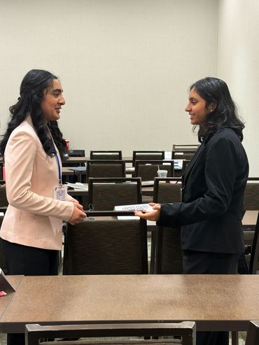 Two women in suits exchanging a document.