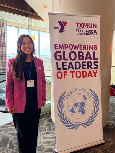 Young woman standing next to TXMUN banner.