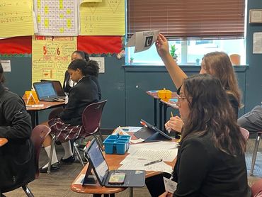 Students engaged in classroom activities using laptops and tablets.