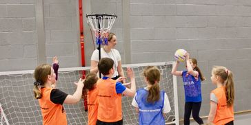 Group of children playing netball in a sports hall