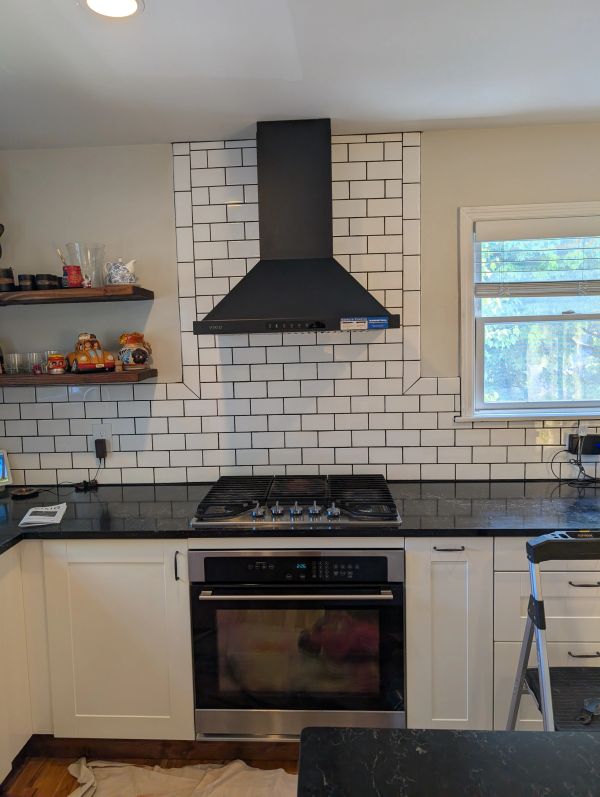 Modern kitchen with black stove, white cabinets, and subway tile backsplash.